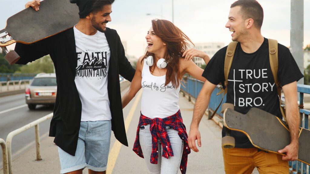 Drei Personen tragen christliche Kleidungsstücke von Christian Apparel - ein schwarzes T-Shirt mit "True story Bro" Aufdruck, ein weißes Top mit "Saved by grace" Aufdruck und ein weißes Shirt mit "Faith can move Mountains" Aufdruck.